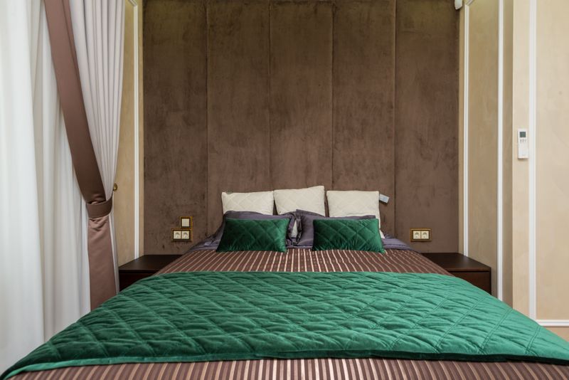 A double bed with green bedding and bedside tables